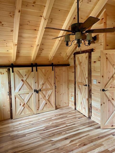 bonus room featuring wooden walls, beamed ceiling, wooden ceiling, and light wood-type flooring