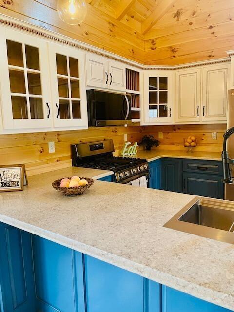 kitchen featuring stainless steel appliances, sink, blue cabinetry, wooden ceiling, and lofted ceiling