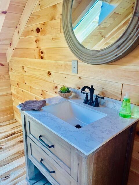 bathroom featuring beam ceiling, vanity, wooden ceiling, and wooden walls