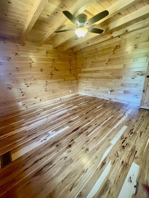 interior space with beamed ceiling, wooden ceiling, and wooden walls