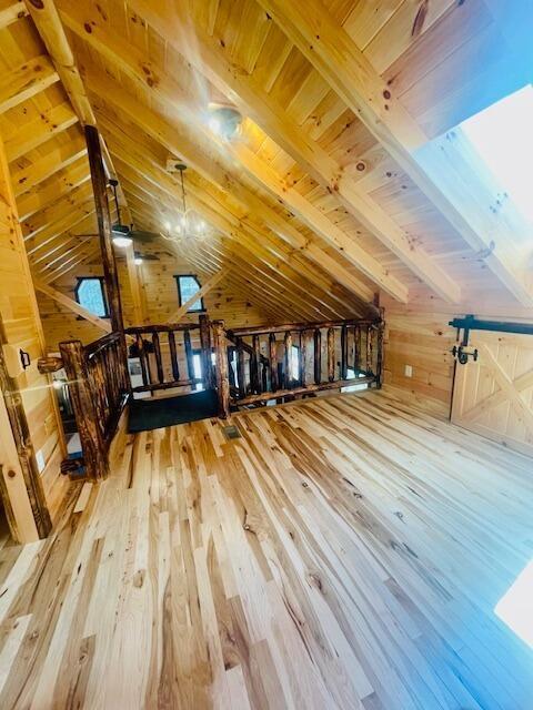 additional living space with vaulted ceiling with beams, wooden walls, hardwood / wood-style floors, and wooden ceiling