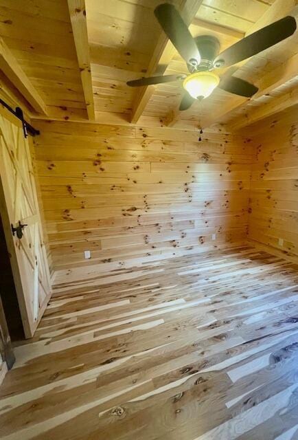 bonus room featuring wood walls, a barn door, beam ceiling, light hardwood / wood-style floors, and wood ceiling