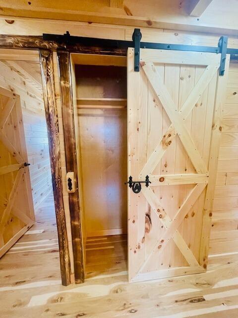 interior space with a barn door, hardwood / wood-style flooring, and wooden walls