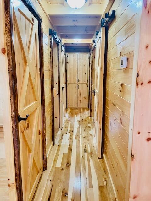 hall featuring light wood-type flooring and wooden walls