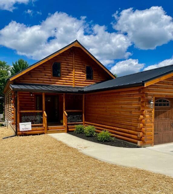 log-style house with a garage and covered porch