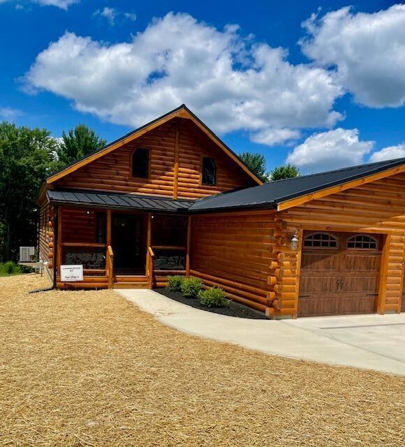 log-style house featuring covered porch and a garage