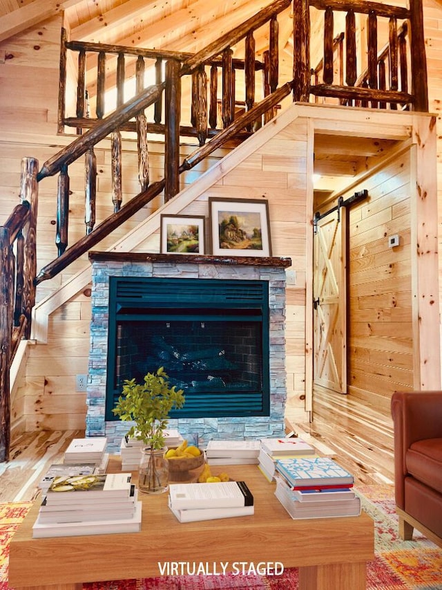 unfurnished living room featuring a barn door, a fireplace, and wooden walls