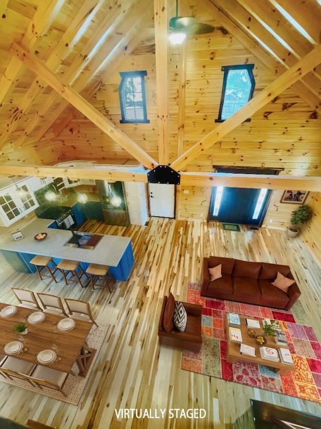 unfurnished living room featuring wooden walls, hardwood / wood-style floors, beamed ceiling, and high vaulted ceiling