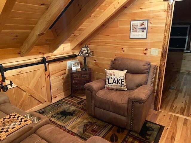 living area featuring wood ceiling, wood finished floors, wooden walls, and beamed ceiling