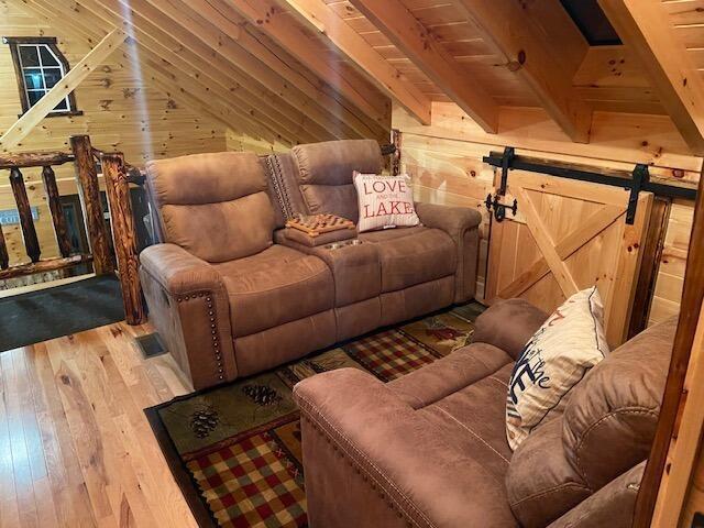 living room featuring wooden walls, lofted ceiling with beams, wooden ceiling, and light wood-style floors