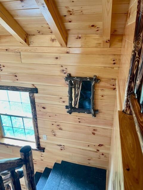 mudroom with wood walls, wooden ceiling, and beamed ceiling