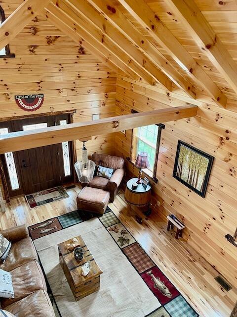living area with wooden walls and beamed ceiling