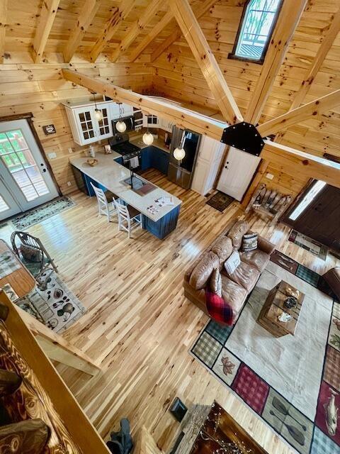 living area with wooden walls, wooden ceiling, beam ceiling, and wood finished floors