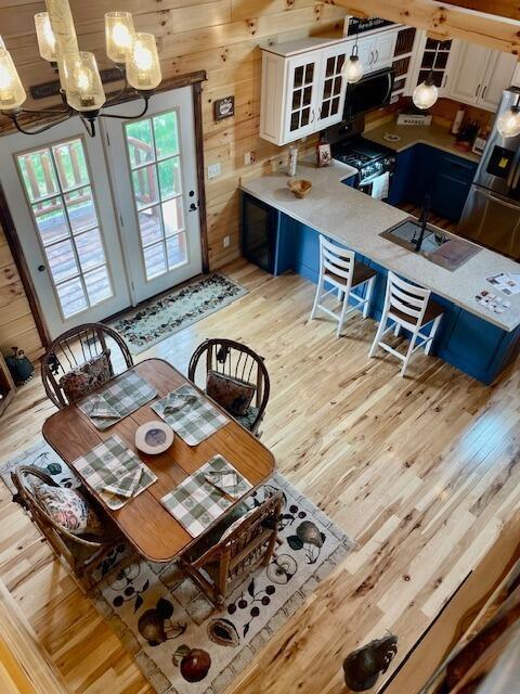 dining space featuring wood walls, an inviting chandelier, and light wood-style floors