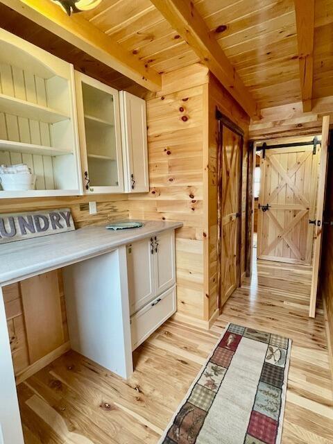 kitchen featuring wooden walls, white cabinetry, beamed ceiling, and wooden ceiling