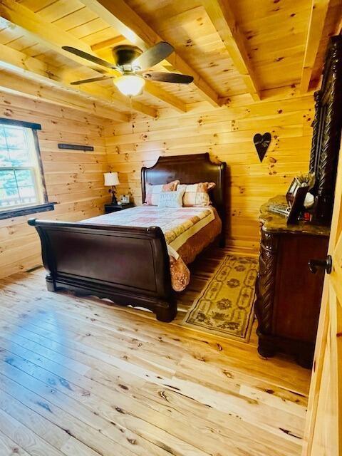 bedroom featuring wood ceiling, wood walls, and beam ceiling