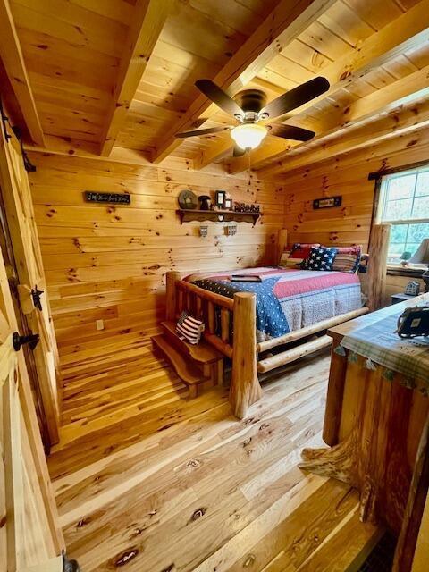 bedroom featuring hardwood / wood-style flooring, wooden walls, wooden ceiling, and beamed ceiling