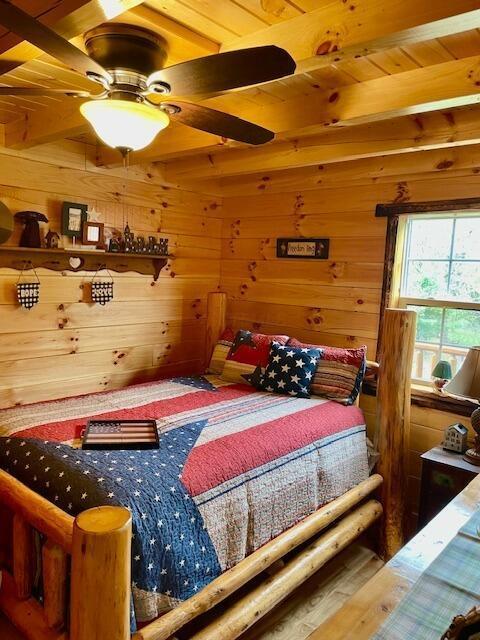 bedroom with wood walls, wooden ceiling, and beamed ceiling