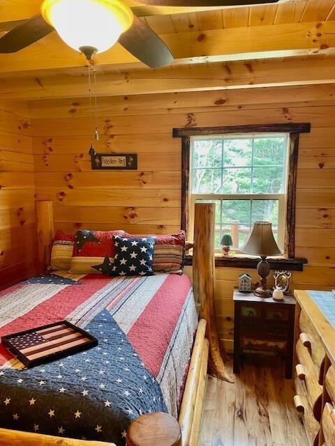 bedroom with wooden walls, wooden ceiling, beamed ceiling, and wood finished floors