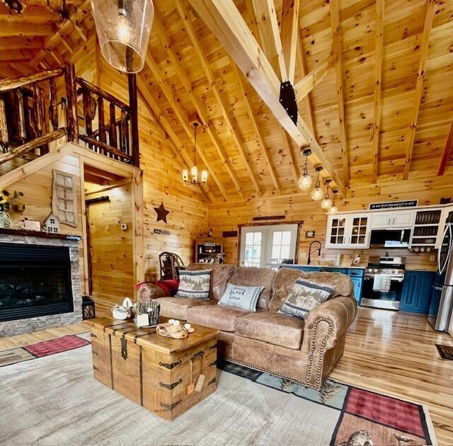 living area featuring wood walls, a fireplace, vaulted ceiling with beams, wooden ceiling, and light wood-style flooring