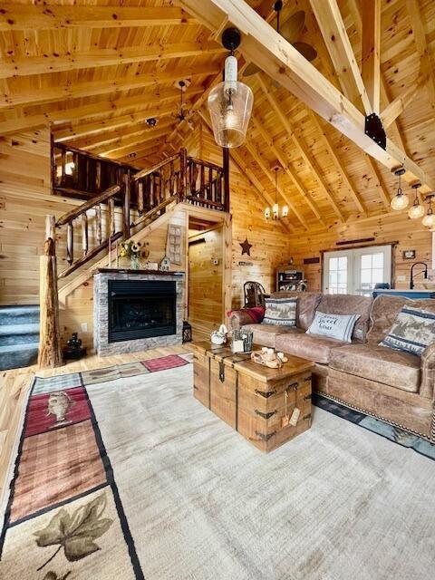 living area with wooden walls, lofted ceiling with beams, wood ceiling, and a fireplace