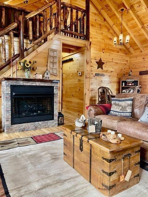living room with wooden walls, lofted ceiling with beams, a fireplace, stairs, and wood ceiling