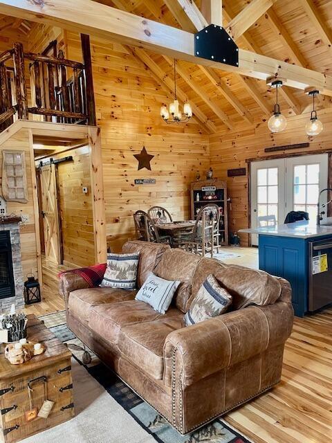 living area with light wood-style floors, wood ceiling, beam ceiling, and wooden walls