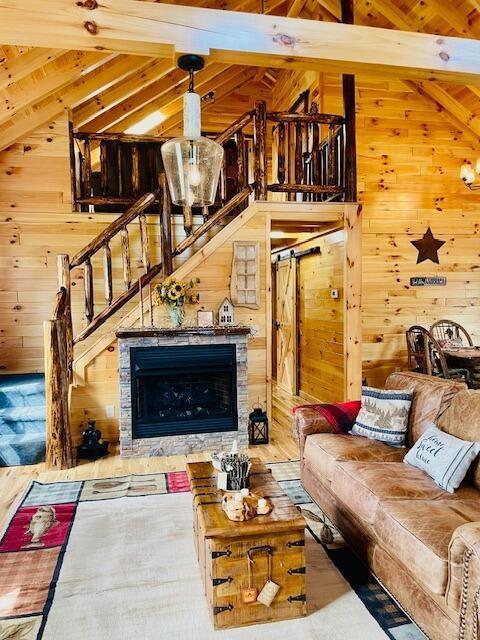 living room with lofted ceiling with beams, wooden walls, and stairway