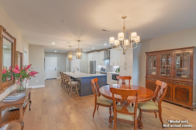 dining space featuring light hardwood / wood-style flooring, a chandelier, and sink