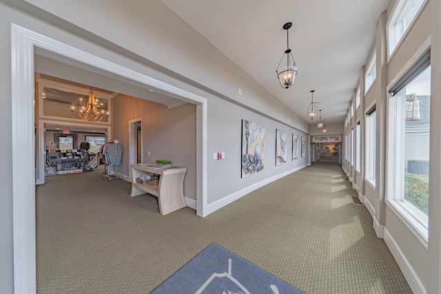 hallway with carpet flooring, a chandelier, and lofted ceiling