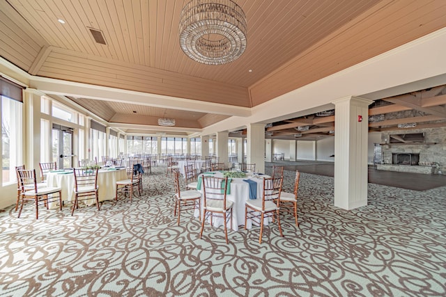 dining space featuring a stone fireplace, wood ceiling, light carpet, and vaulted ceiling