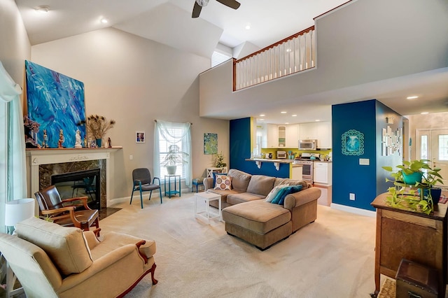 living room with ceiling fan, light colored carpet, a premium fireplace, and high vaulted ceiling