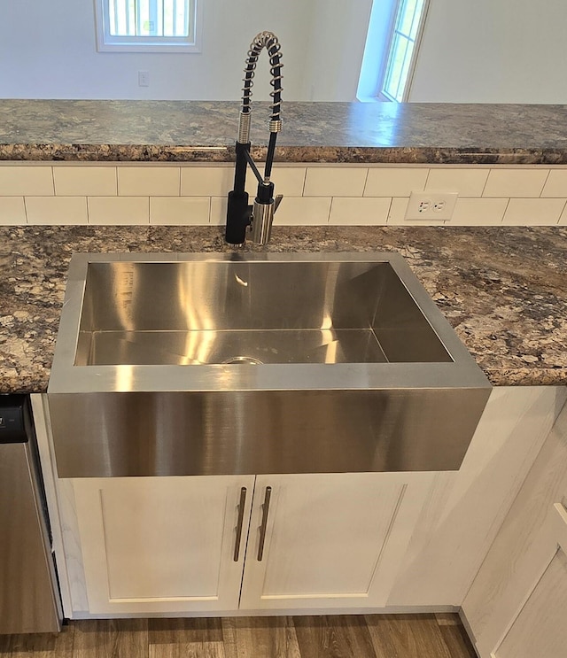 details featuring dishwasher, white cabinets, sink, dark stone countertops, and dark hardwood / wood-style flooring