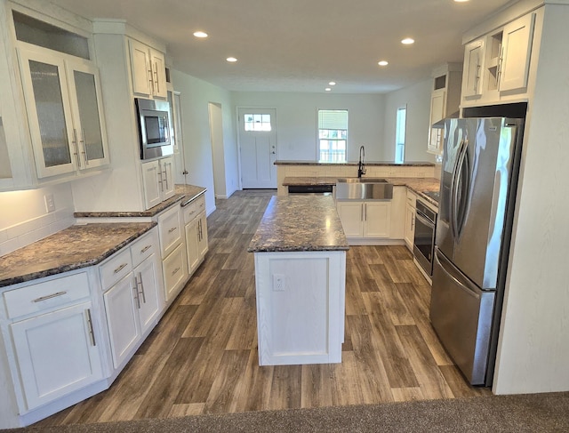 kitchen with dark hardwood / wood-style flooring, dark stone counters, stainless steel appliances, sink, and white cabinets