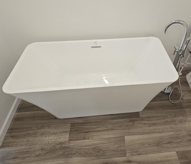 interior details with a tub to relax in and hardwood / wood-style flooring