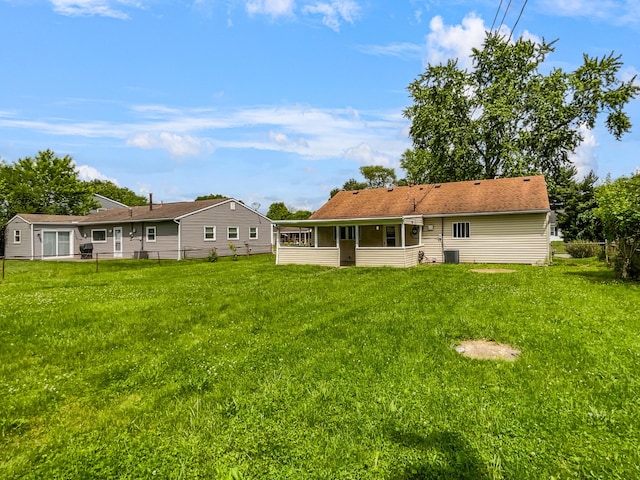 back of property featuring central AC unit, a lawn, and a sunroom