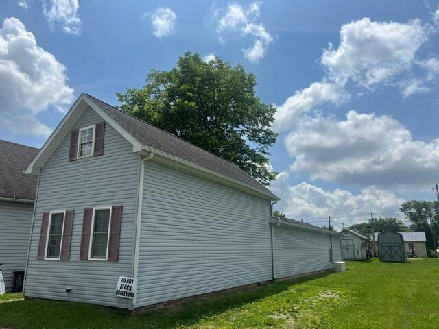 view of property exterior with a yard and a storage unit