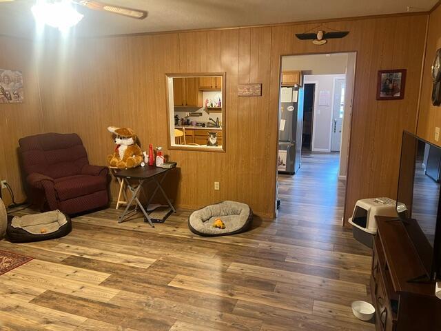 sitting room featuring wooden walls, ceiling fan, and hardwood / wood-style flooring