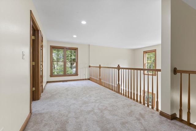 hall featuring light colored carpet and a healthy amount of sunlight