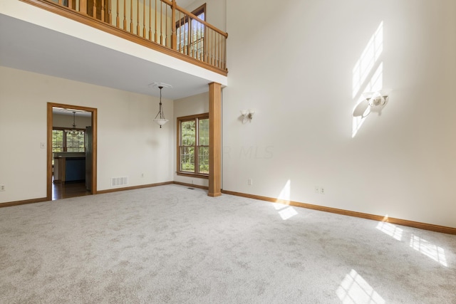 carpeted empty room featuring a healthy amount of sunlight and a high ceiling