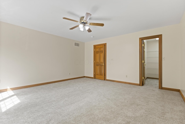 unfurnished bedroom with a spacious closet, a closet, ceiling fan, and light colored carpet