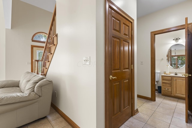 hall with a wealth of natural light, sink, and light tile patterned floors