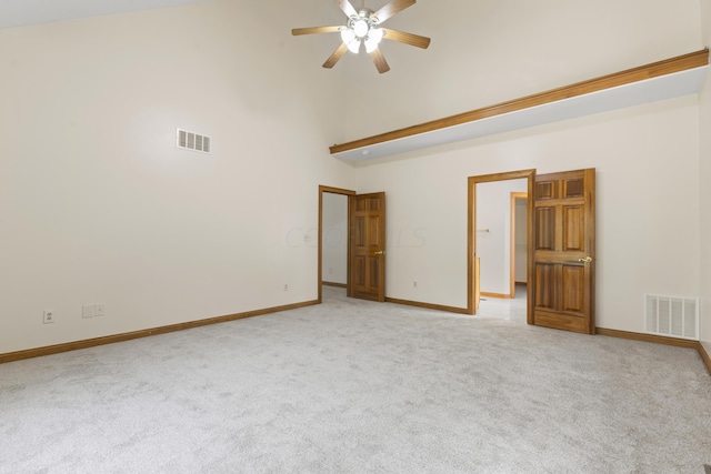 carpeted spare room with ceiling fan and a high ceiling