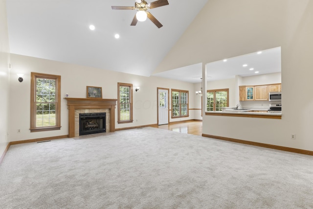 unfurnished living room featuring plenty of natural light, ceiling fan, and high vaulted ceiling