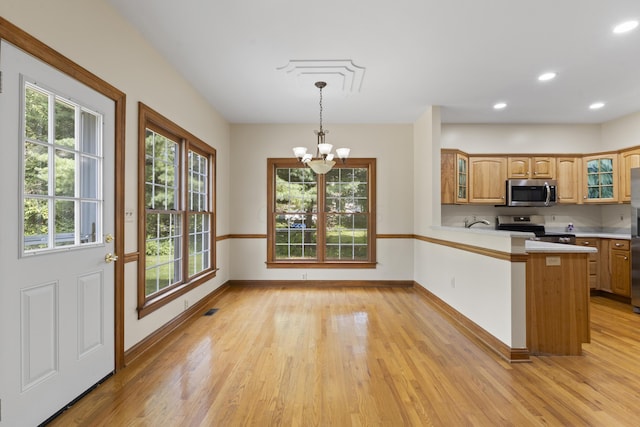 kitchen featuring kitchen peninsula, pendant lighting, stainless steel appliances, and a wealth of natural light