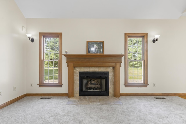 unfurnished living room with light carpet, a tile fireplace, and plenty of natural light