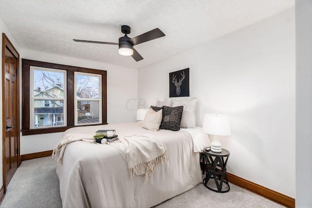 bedroom featuring ceiling fan, light colored carpet, and a textured ceiling