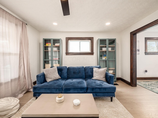 living room featuring a textured ceiling, light hardwood / wood-style floors, and ceiling fan