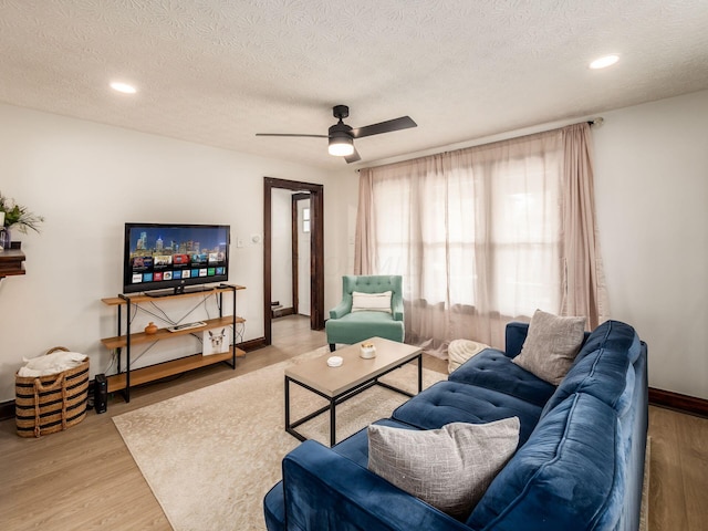 living room featuring hardwood / wood-style floors, ceiling fan, and a textured ceiling