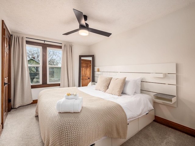 bedroom with ceiling fan, light carpet, and a textured ceiling